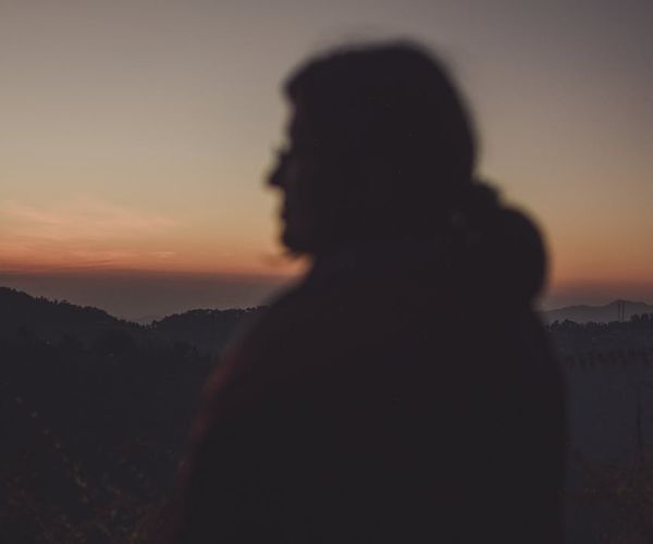 Silhouette of a man meditating with a calm blue background.